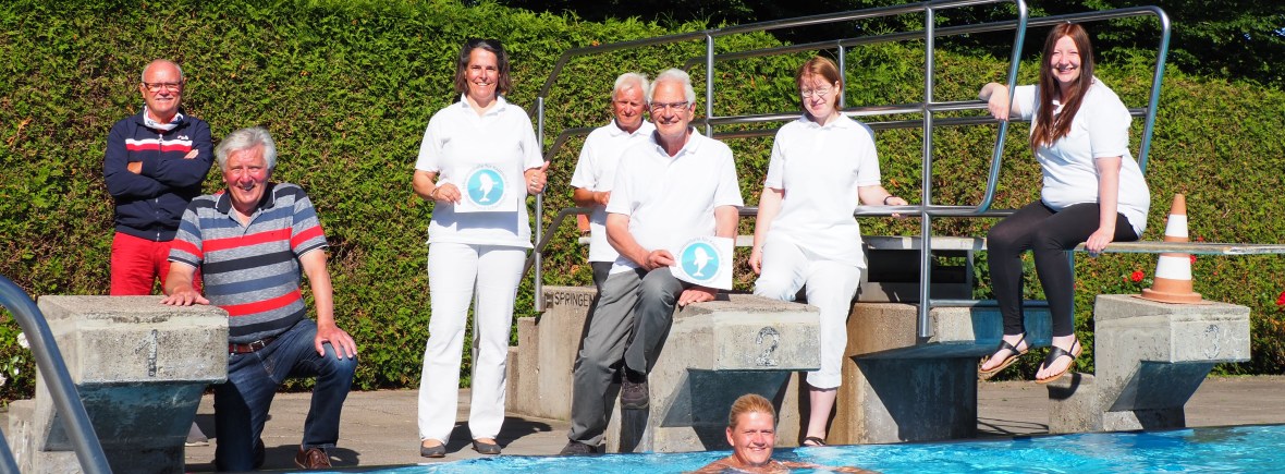 Acht Personen in einem Freibad schauen in die Kamera