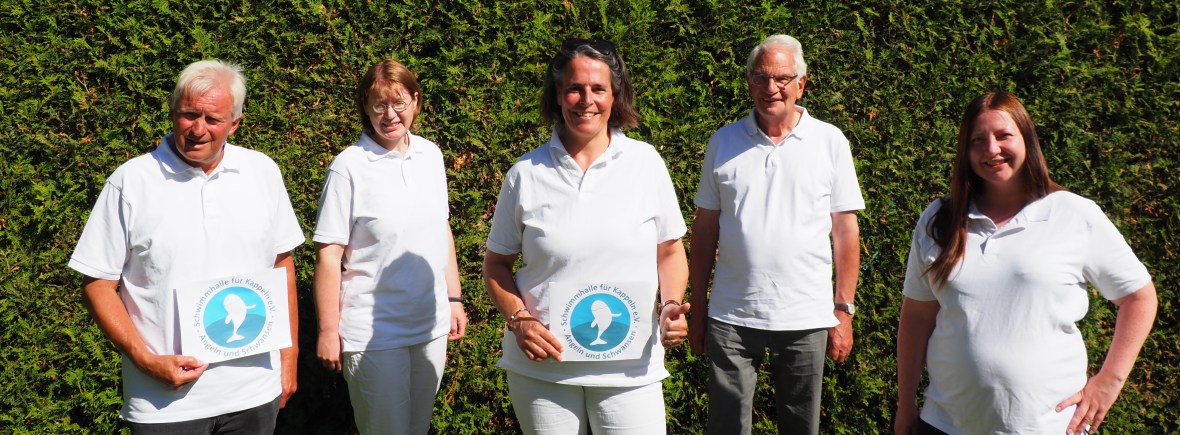 Drei Frauen und zwei Männer stehen vor einer Hecke und lachen in die Kamera