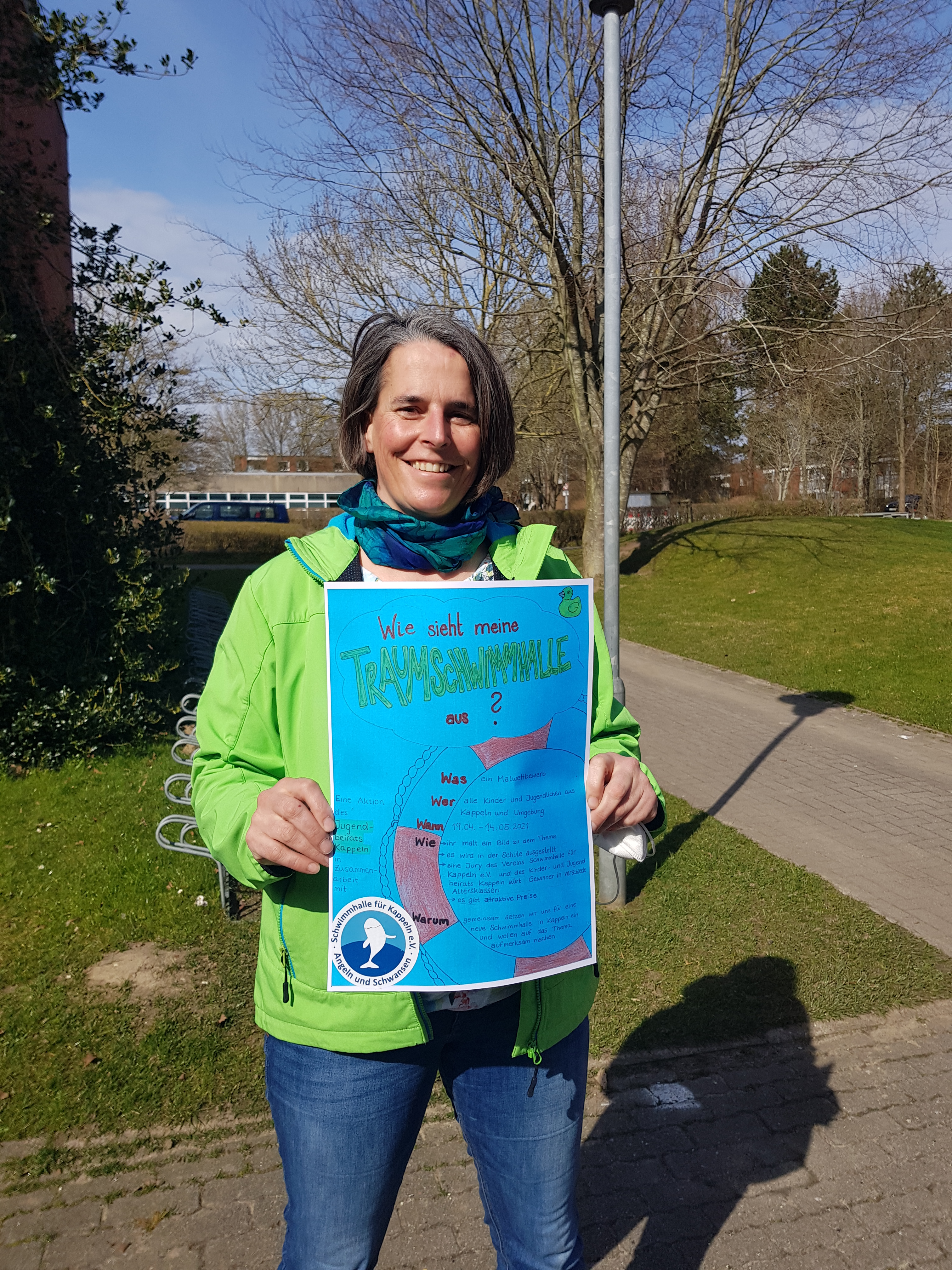 Eine Frau zeigt ein Plakat für einen Schülermalwettbewerb in die Kamera