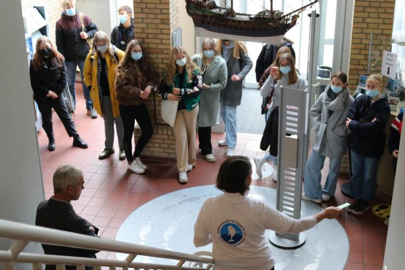 Schülerinnen und Schüler stehen im Kappelner Rathaus, eine Frau erklärt etwas